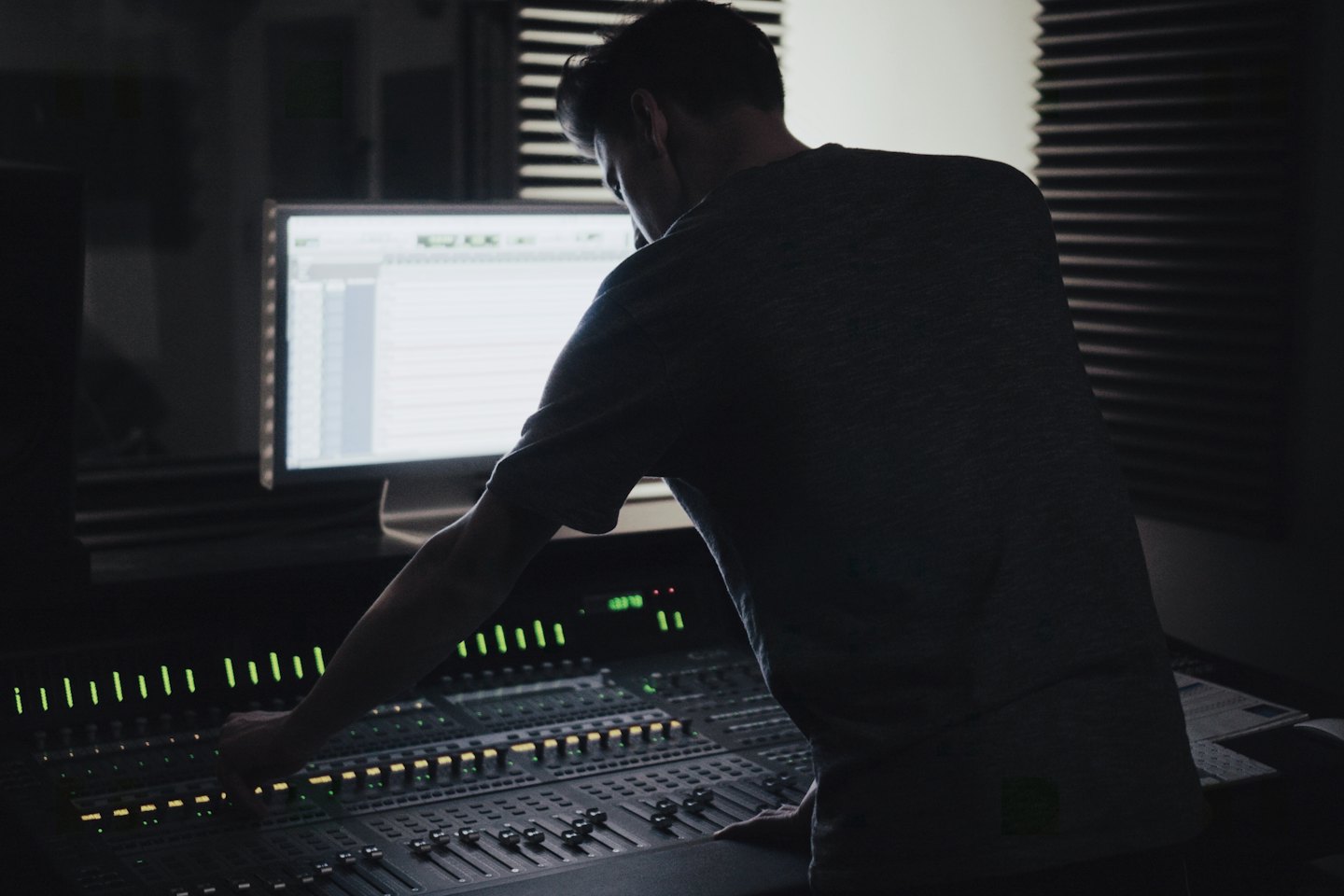 Ingegnere audio che regola i fader su una console di missaggio.