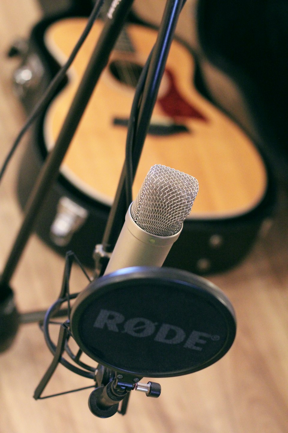Un microfono a condensatore e una chitarra acustica all'interno di uno studio di registrazione.